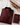 Folded burgundy abaya with braided trim beside a passport holder and luxury cream suitcase